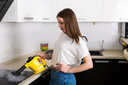 Woman cleaning kitchen with steam cleaner
