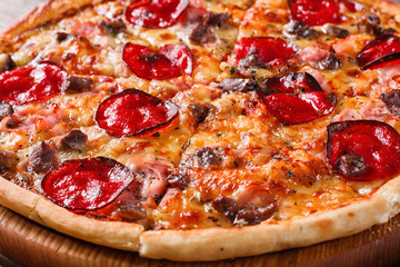 Appetizing tasty baked pizza with bacon, meat, salami and cheese, close up. Italian national food, traditional cuisine.