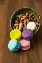 Tasty macaroons and cup of milk with almond on wooden background