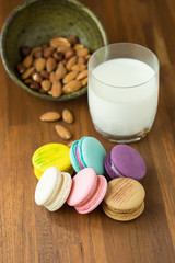 Tasty macaroons and cup of milk with almond on wooden background