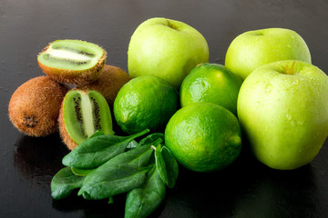 Fototapeta na wymiar Ingredients for smoothie. Green fruits on black wooden background. Apple, lime, spinach, kiwi. Detox. Healthy food.
