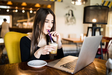 Beautiful woman drink coffee and look at laptop at cafe