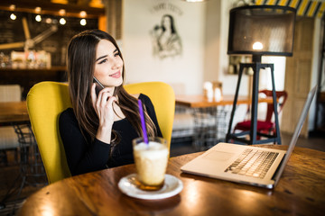 Young woman talking on the phone in coffee shop