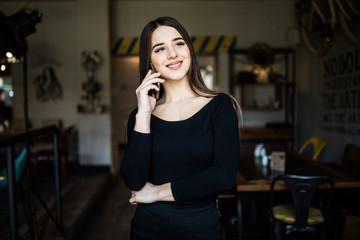 Young beauty smiling woman standing in a cafe and talking on the cellphone