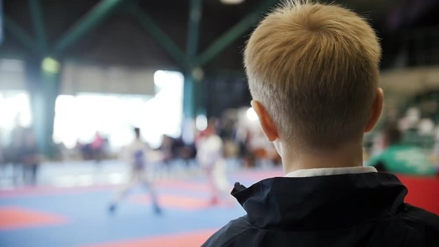 Karate championship - teenager boy watching karate fighting - spectator at competition, slow-motion