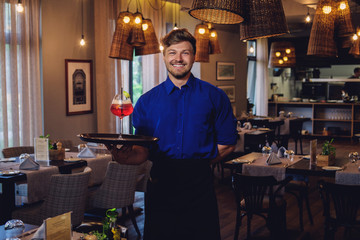 Waiter with alcoholic cocktail for customer.