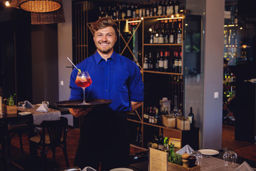 Waiter with alcoholic cocktail for customer.