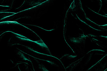 Dark green velvet background. Luxurious shiny material.