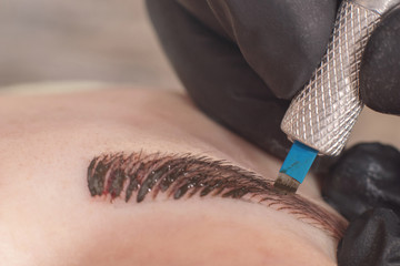 Cosmetologist applying permanent make up on eyebrows. Permanent tattooing of eyebrows.