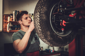Obraz na płótnie Canvas Mechanic working on classic car wheels and suspension in restoration workshop