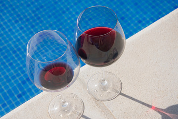 A bottle of red wine by the pool. Day, water and glass