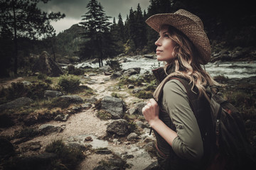 Beautiful woman hiker near wild mountain river.