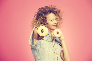 the hand of the girl with the donuts on pink background