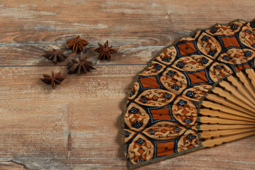 Star anise and fan on brown wooden background.