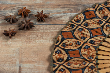 Star anise and fan on brown wooden background.