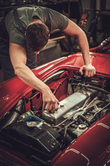 Mechanic working on classic car electrics in restoration workshop