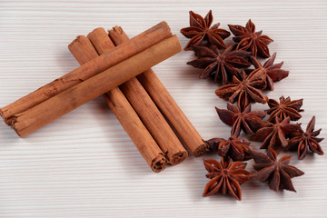 Cinnamon sticks and star anise on white wooden background.