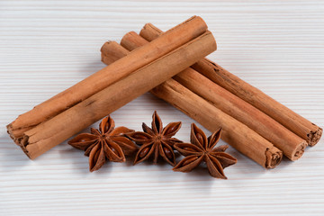 Cinnamon sticks and star anise on white wooden background.