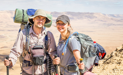 Couple tourists backpackers standing desert mountain peak ridge.