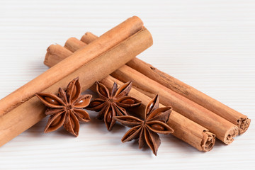 Cinnamon sticks and star anise on white wooden background.
