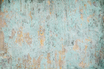 Weathered, faded and peeled off turquoise concrete wall texture background with vignetting.
