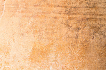 Weathered, aged and scratched orange concrete wall texture background.