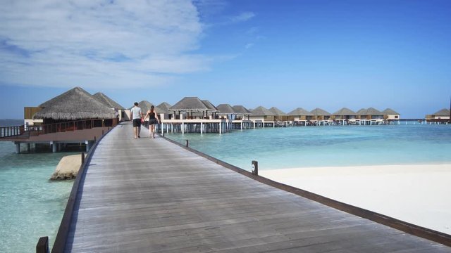 Tourist Couple Strolling on Pier at Vaadhoo Island, Maldives Resort