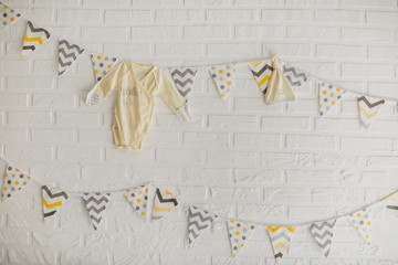 Flags and clothes of a baby hanging on a white stone wall in the Studio