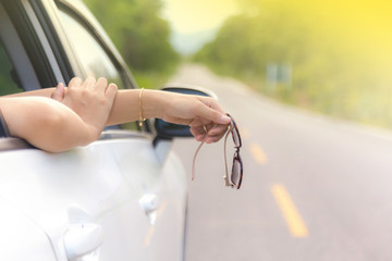 Woman hand at the car window on an country road