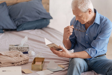 Serious elderly man reading an old postcard