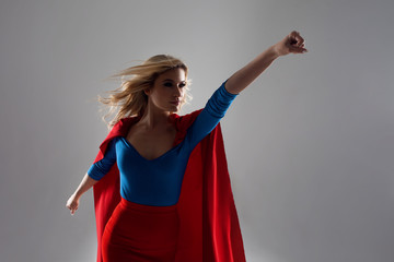 Superhero Woman. Young and beautiful blonde in image of superheroine in red Cape growing © Ulia Koltyrina