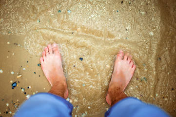 Feet on the beach in the sea and sand. Top view