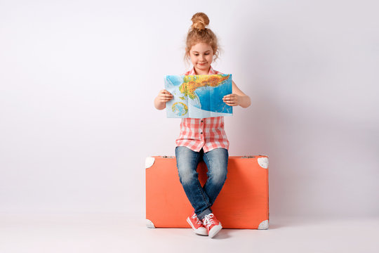 Child blonde girl with pink vintage suitcase and city map ready for summer vacation. Travel and adventure concept