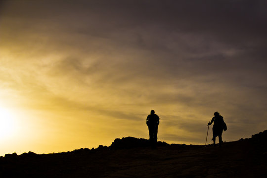 silhouettes on top of mountain in sunset
