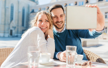 Young couple drinking coffee and having fun with tablet in the cafe. Love, dating, technology, lifestyle