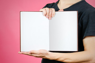 Closeup of guy in black t-shirt holding blank open white book on isolated background. Education concept. Mock up
