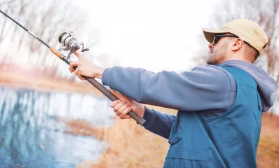 Selbstklebende Fototapeten Young angler enjoys in fishing on the river. Sport, recreation, lifestyle © bobex73