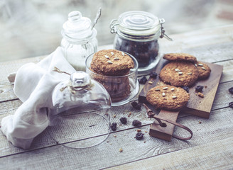 Oatmeal cookies in glass jars on wooden table. Homemade cookies stacks, raisin, sunflower seeds. Close-up
