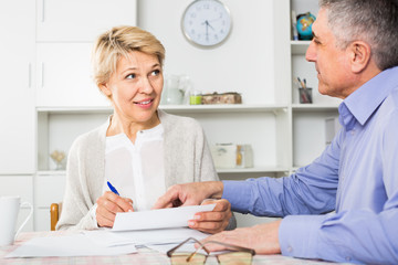 Obraz premium calm mature couple at table attentively study documents