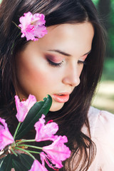 Outdoor fashion photo of beautiful young woman surrounded by flowers. Spring blossom