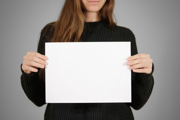 Girl holding white A4 blank paper. Leaflet presentation. Pamphlet hold hands. Woman show clear...