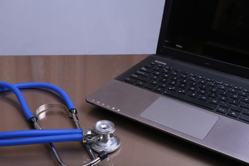Obraz na płótnie Canvas A medical stethoscope near a laptop on a wooden table