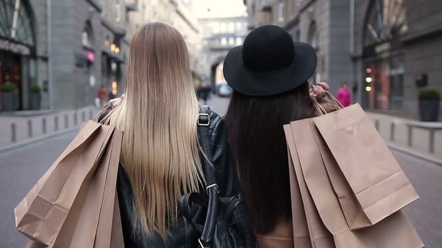 Back view of two walking women with shopping bags