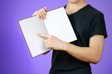 Closeup of guy in black t-shirt holding blank open white book on isolated background. Education concept. Mock up