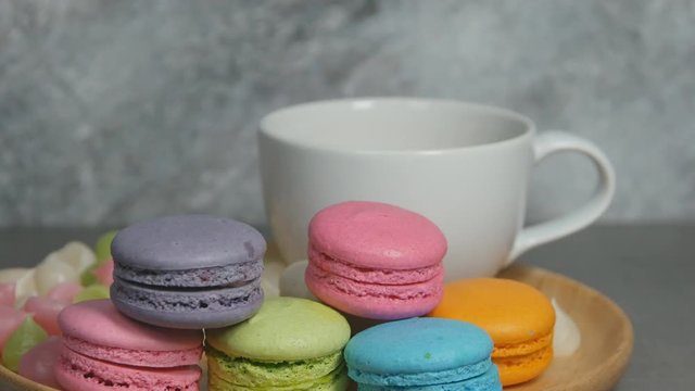 4k of a woman's hand picking colorful macaroons dessert food on dish