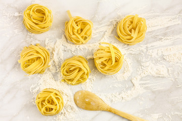 Overhead photo of pasta nests on white marble