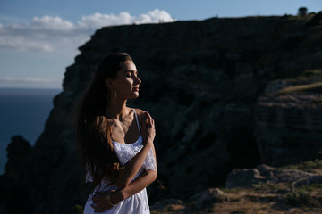 Beautiful woman in white dress on blue sea and sky background in sunset.