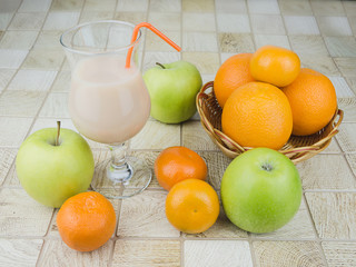 cocktail with a straw on the table with fresh apples and oranges