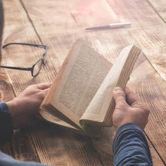 Naklejka premium Man reading book sitting at a wooden table
