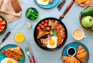 Fried eggs, bacon, tomatoes, beans and spinach in frying pan